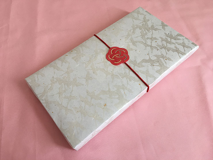 日英の説明書、包装紙は白い厚手の和紙で鶴のデザイン。赤のゴムと水引きシールでお届けします。